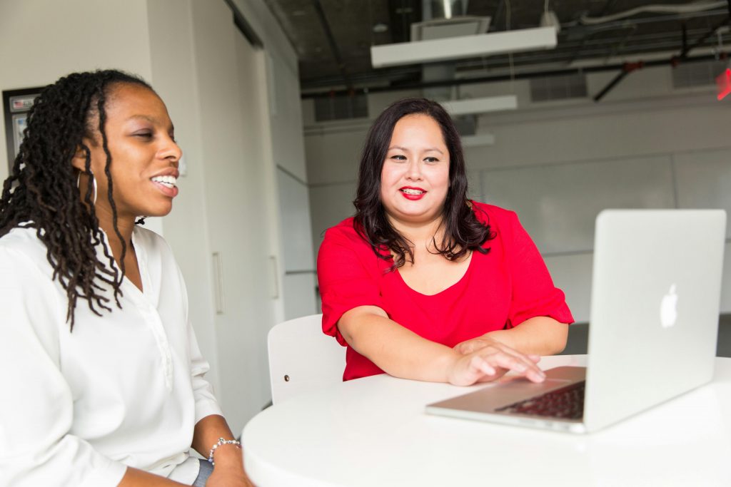 woman showing another woman on laptop